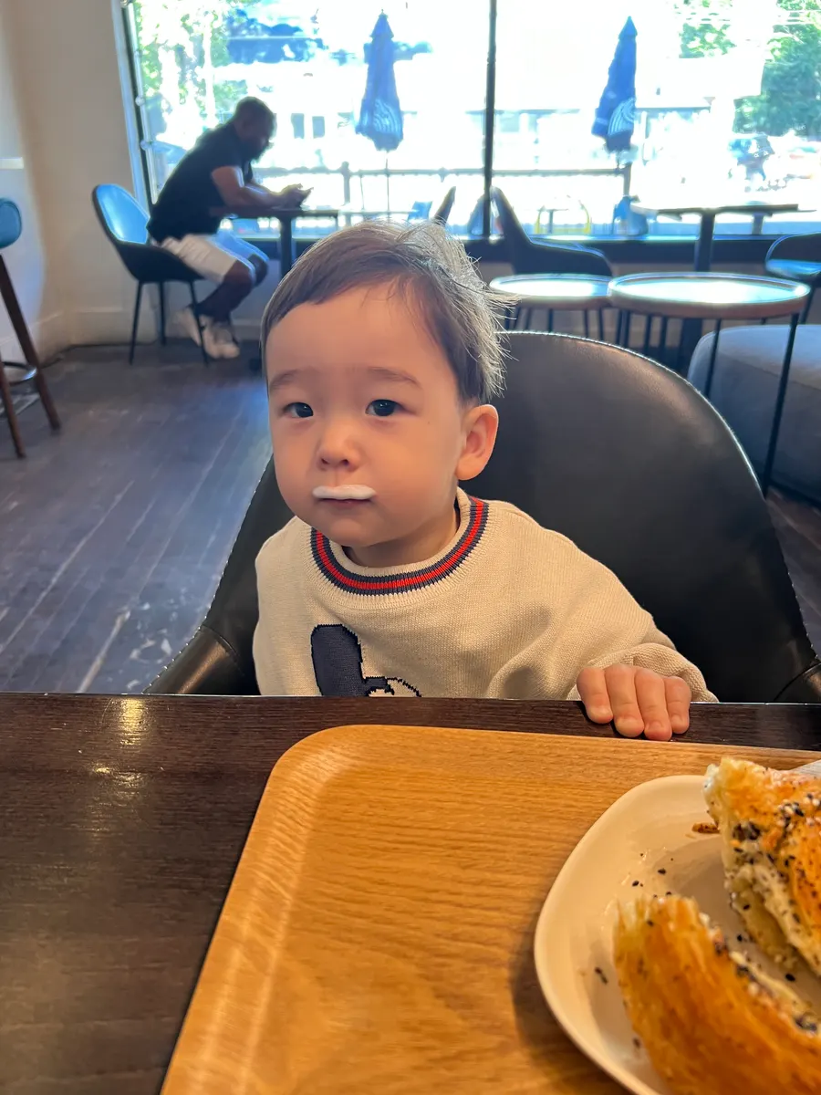 Amadeus at 21 months in a café high chair with a milk mustache
