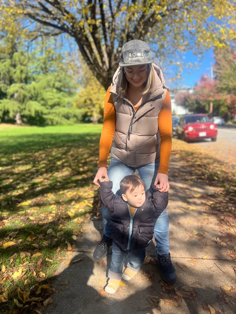 Amadeus at 11 months holding mama's hands on an autumn sidewalk